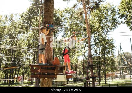 Little funny kids climbs on net in rope park Stock Photo