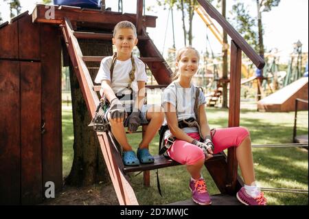 Little girl and boy sitting on stairs in rope park Stock Photo