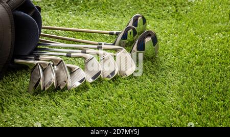 Golf clubs set in a bag on green course lawn, shiny stainless steel, close up view. Golfing sport and equipment concept, copy space. Stock Photo