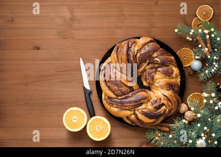 chocolate Christmas grandmother in the form of a wreath with orange syrup on a plate cut into pieces. Christmas decorations on a wooden table. Stock Photo