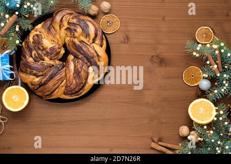 chocolate Christmas grandmother in the form of a wreath with orange syrup on a plate cut into pieces. Christmas decorations on a wooden table. Stock Photo