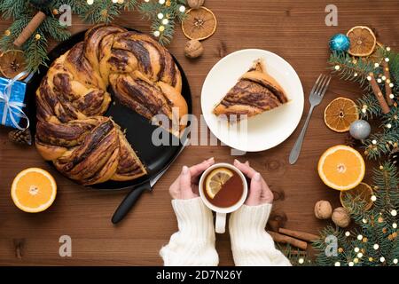 chocolate Christmas grandmother in the form of a wreath with orange syrup on a plate cut into pieces. Christmas decorations on a wooden table. Stock Photo