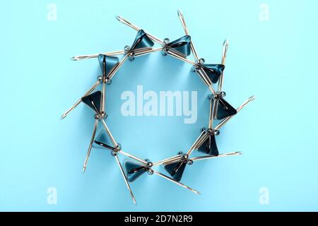 A circle made of binder clips on blue background. Stock Photo