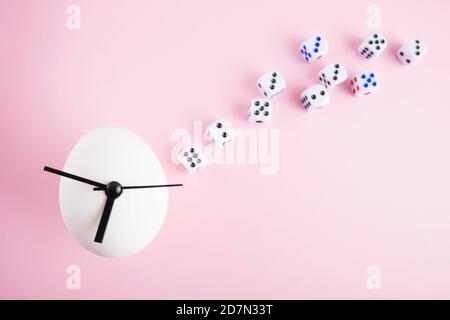 Egg clock and dice on pink background. Stock Photo