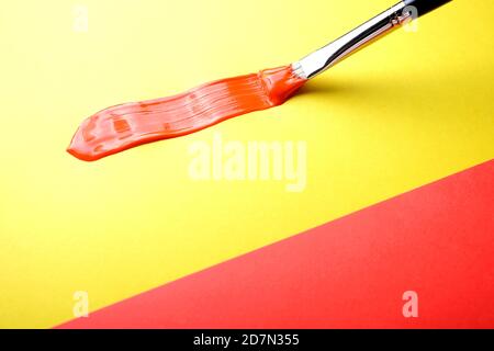 Red brush stroke made with red oil paint on yellow Stock Photo