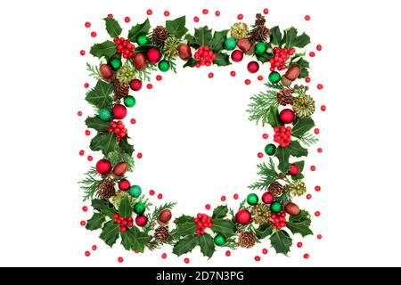 Christmas abstract square wreath decoration with holly, loose berries, red & green bauble decorations & winter greenery on white background. Stock Photo