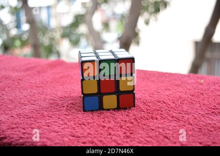 Unsolved Rubik's Cube on the red Background Stock Photo