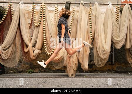 Woman jumping in front of some fishing nets hanging on the wall Stock Photo