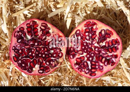 Two halves of a sliced fresh pomegranate with juicy seeds, ready to eat Stock Photo