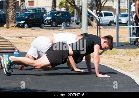 two young men doing pushups outdoors during an exercise or gym training session concept health and fitness lifestyle Stock Photo