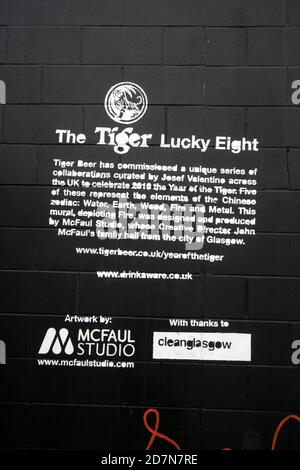Glasgow, Clydeside, Scotland, UK. Explanation of a large mural of a tiger painted on riverside wall along side the River Clyde, The mural painting was commissioned by a company called Tiger Beer in collaboration with artists. Different art work representing the elements of the Chinese Zodiac , water, earth, wood, fire and metal. This mural depicting fire was designed and produced McFaul Studio, whose creative director John McFaul hail from Glasgow Stock Photo