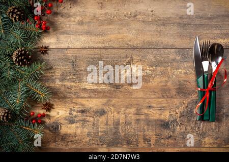 festive New Year Christmas dinner concept. Christmas decorations and Cutlery on a dark rustic table. Christmas table place setting. Winter holidays ba Stock Photo