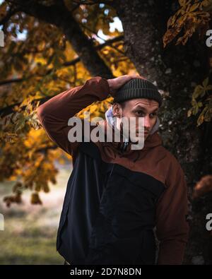 Young man in warm clothes walking in the outside in the autumn forest. Fall mood Stock Photo