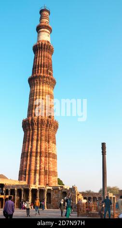 New Delhi, 22, March,2017: Low angle of tapering tower Qutub Minar and Black iron pillar at Qutub Complex known as Unesco Heritage,New Delhi,India Stock Photo
