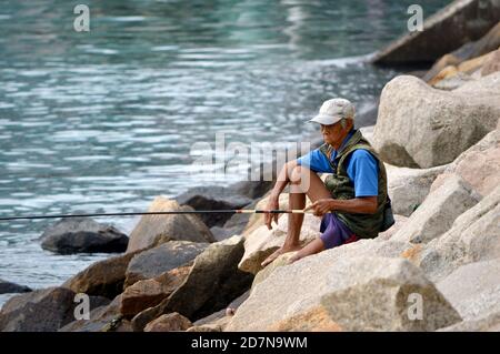 Old man fishing along Rambler Channel, Tsuen Wan, Hong Kong Stock Photo