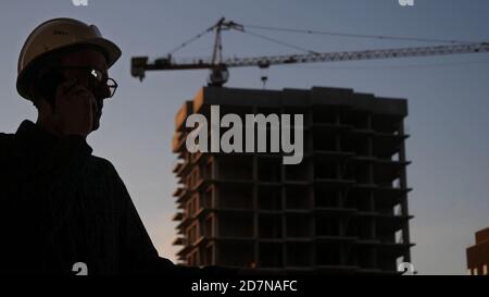 Engineer in a white hard hat talking on the phone. Silhouette. Stock Photo