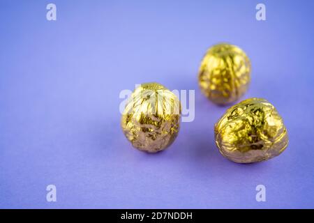 Three walnuts colored in golden color on a violet background. Selective focus Stock Photo