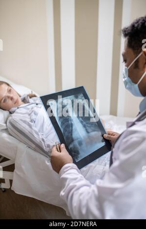 Male radiologist looking at lung x-ray image of sick female patient with covid Stock Photo
