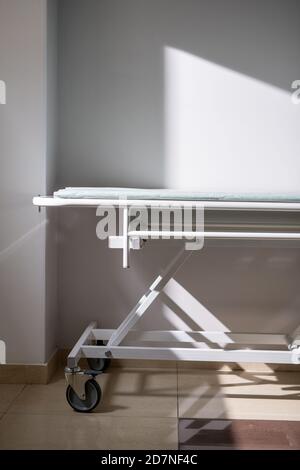 Empty medical cart standing by wall and window in hospital chamber or corridor Stock Photo