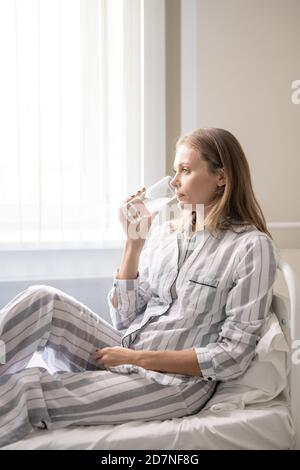 Young female patient of covid hospital having glass of water or taking pills Stock Photo