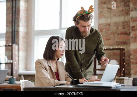Young serious businessman with xmas headband explaining data on laptop display Stock Photo