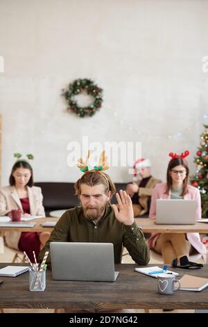 Young happy male office manager looking at laptop display and waving hand Stock Photo