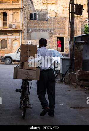 Jaisalmer, Rajasthan / India - september 24 2020 : Old man transporting carton boxes on cycle passing through the streets Stock Photo