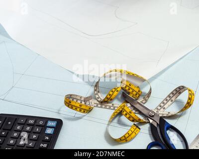 tailor's measure tape and scissors on paper pattern layout of dress at home Stock Photo