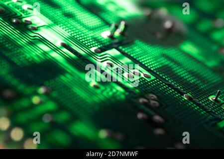 Illuminated fresh green electronic circuit board with many electrical components. Narrow depth of field Stock Photo