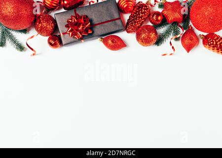 Christmas red traditional decorations, gift box and fir branches on white background with copy space, flat lay. Stock Photo