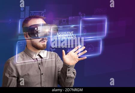 Businessman looking through Virtual Reality glasses with ASSISTIVE TECHNOLOGY inscription, new technology concept Stock Photo