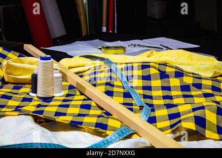 Blue and yellow checkered fabric with ruler and meter on sewing table Stock Photo
