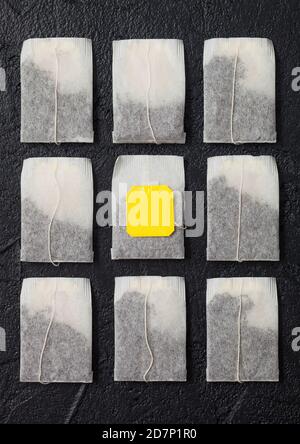 Teabags of black tea with yellow tag on black background. Top view Stock Photo