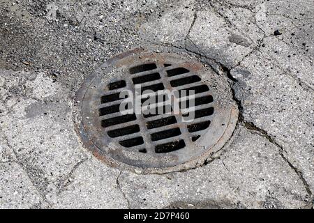 Rusty drainage grate in cracked aspahlt Stock Photo