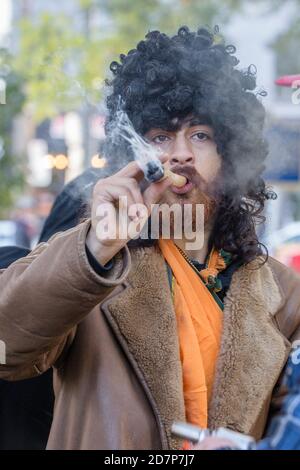 A man wearing a black curly wig smoking a big joint during the cannabis  legalization celebration day at Trinity Bellwoods Park Stock Photo