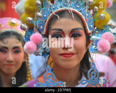 Costumed female Thai Chinese performers with painted traditional Peking opera masks pose for the camera at colorful Chinese New Year street parade. Stock Photo