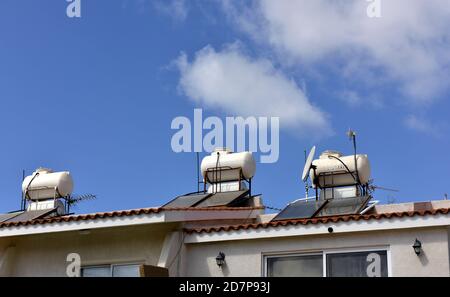 Houses with solar thermal heating hot water storage on the roof along with satellite dish and TV aerial, Cyprus Stock Photo