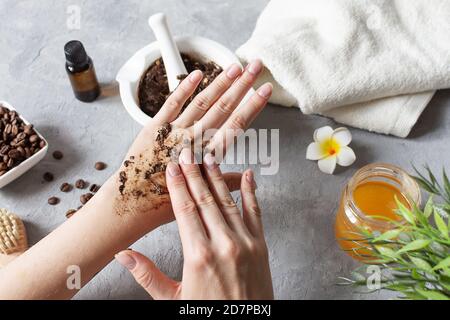 Woman hands making peeling with homemade body scrub made with ground coffee, honey and oatmeal over gray concrete table. Self-care at home, eco homema Stock Photo