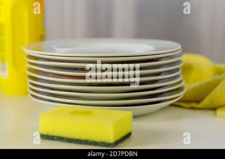 Bottle of dishwashing liquid and stack of utensils isolated on white Stock Photo