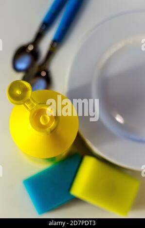 Bottle of dishwashing liquid and stack of utensils isolated on white Stock Photo