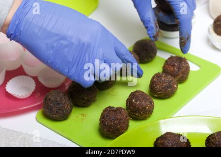 A woman puts dried fruit and nuts sweets on a plate. Made at home in self-isolation during the epidemic. Stock Photo