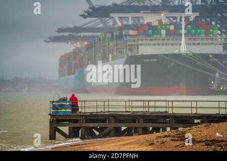 Sea Fishing in the rain in the shadow of large container ships unloading at  Felixstowe Port. Port of Felixstowe sea fishing. Stock Photo