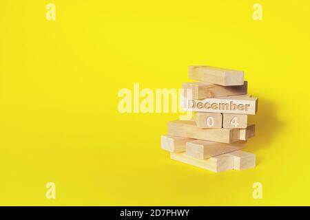 December 4th. Day 4 of month, Calendar date. Wooden blocks folded into the tower with month and day on yellow background, with copy space. Winter mont Stock Photo