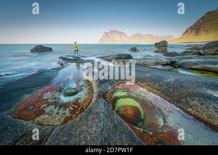Woman standing on rocks on the beach, in front tide pool with formation Eye of Utakleiv, Vestvagoy, Nordland, Lofoten, Norway Stock Photo