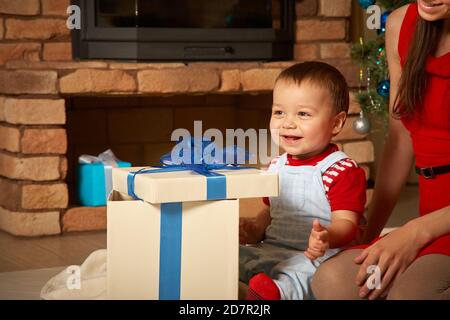 Mother gives Christmas gift to his little son for a New Year. Mom and son  opening Christmas presents Stock Photo - Alamy