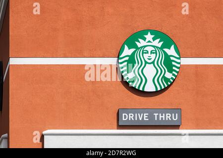 Gainesville, USA - April 27, 2018: Sign logo closeup for Starbucks coffee shop isolated on wall in Florida and text for drive thru through for conveni Stock Photo