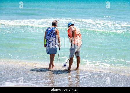Sanibel Island, USA - April 29, 2018: Bowman's beach in Florida with colorful turquoise water on sunny day senior vacation couple standing shelling eq Stock Photo