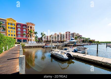 Naples, USA - April 30, 2018: Bayfront residential community center with water harbor marina dock boardwalk and boats palm trees sun flare Stock Photo