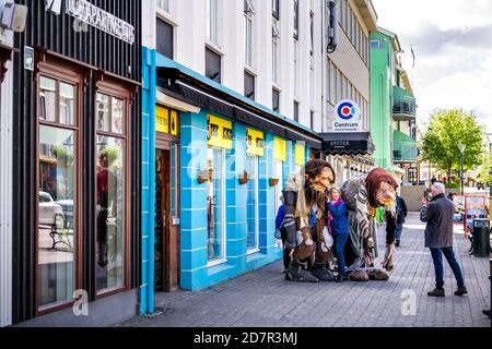 Akureyri, Iceland - June 17, 2018: Small town village city with people on street sidewalk in summer man taking picture of troll statue at viking souve Stock Photo