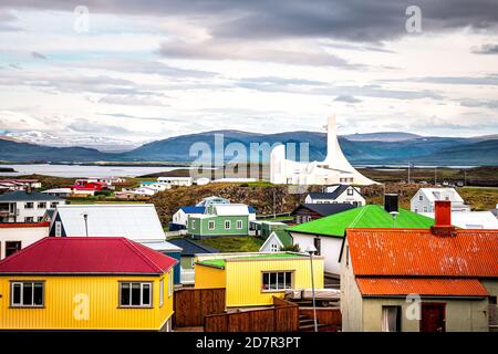 Stykkisholmur, Iceland - June 17, 2018: Modern white church on Snaefellsnes peninsula in Vesturland, Iceland with colorful multicolored buildings with